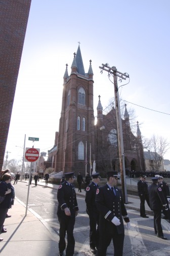 Firefighters stand in the shadow of St. Patrick's Church after Lt. Edward Walsh's wake. Photo by Charlie Breitrose