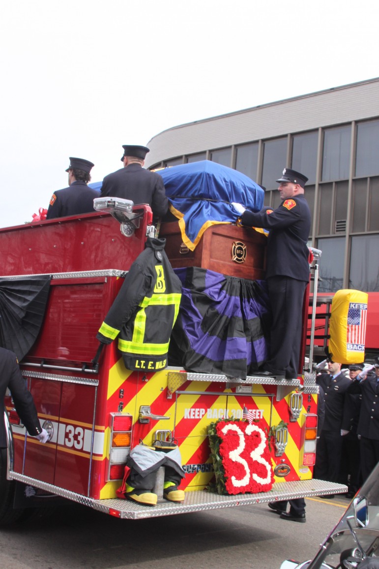Lt. Edward Walsh's fire gear hangs off Boston Engine 33, which is carrying his coffin to the funeral.