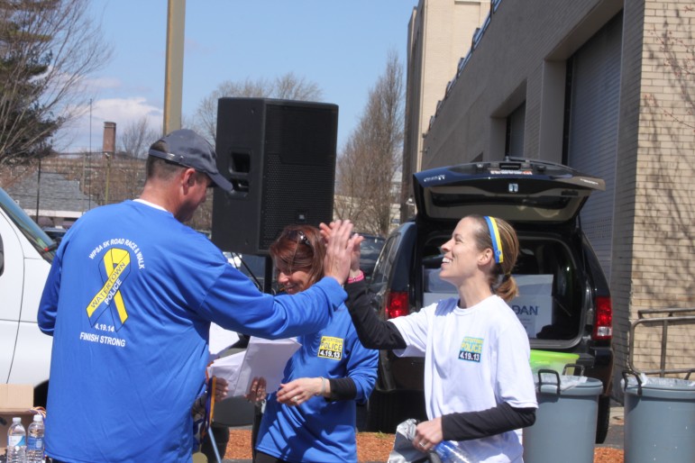Top female runner Jill Wilder of Waltham gets a high five from Watertown Police Lt. Michael Lawn, the Finish Strong Road Race organizer.