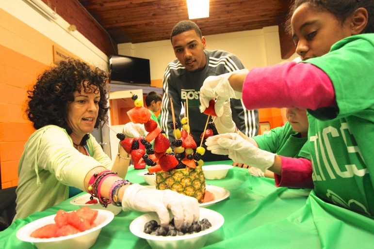 Boston Celtics player Phil Pressey watches kids at the Watertown Boy's & Girl's Club make healthy desert creations.
