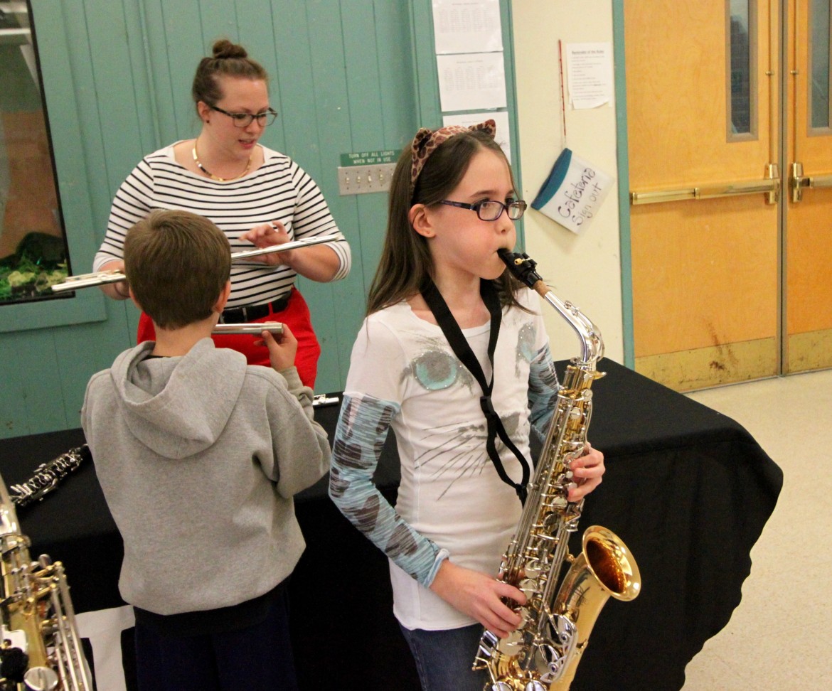 A young musician tries out a saxophone at the petting zoo during MusicFest.