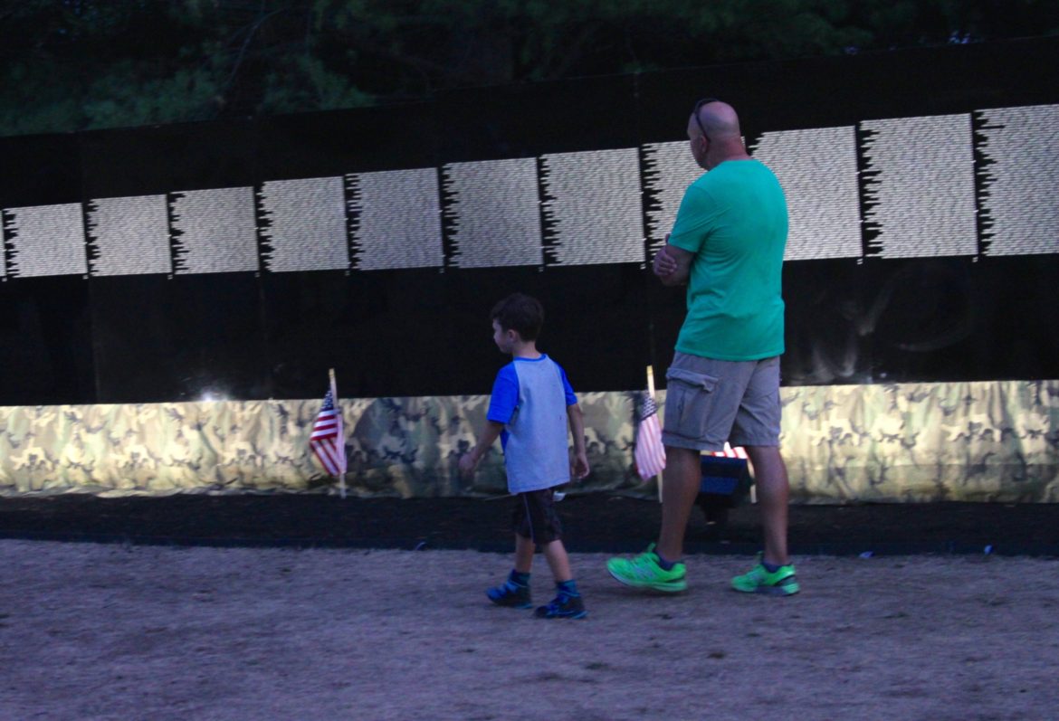 A man and his son look at names on the traveling Vietnam Memorial Wall visiting at Gore Place this week.
